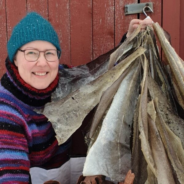 Bildet viser Grete Julie Lerdalen som holder en mengde fiskeskinn i hånden