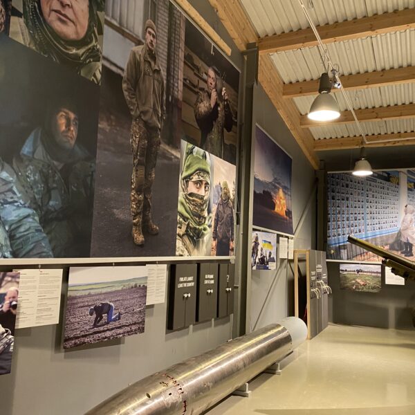 Krigsfoto i ulike størrelser hengende på en museumsvegg. Foto
