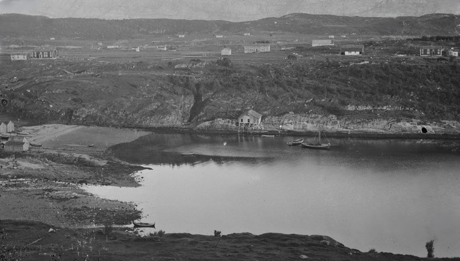 Mørkt landskap med en fjord omgitt av lave åser i skumring. s/hv foto